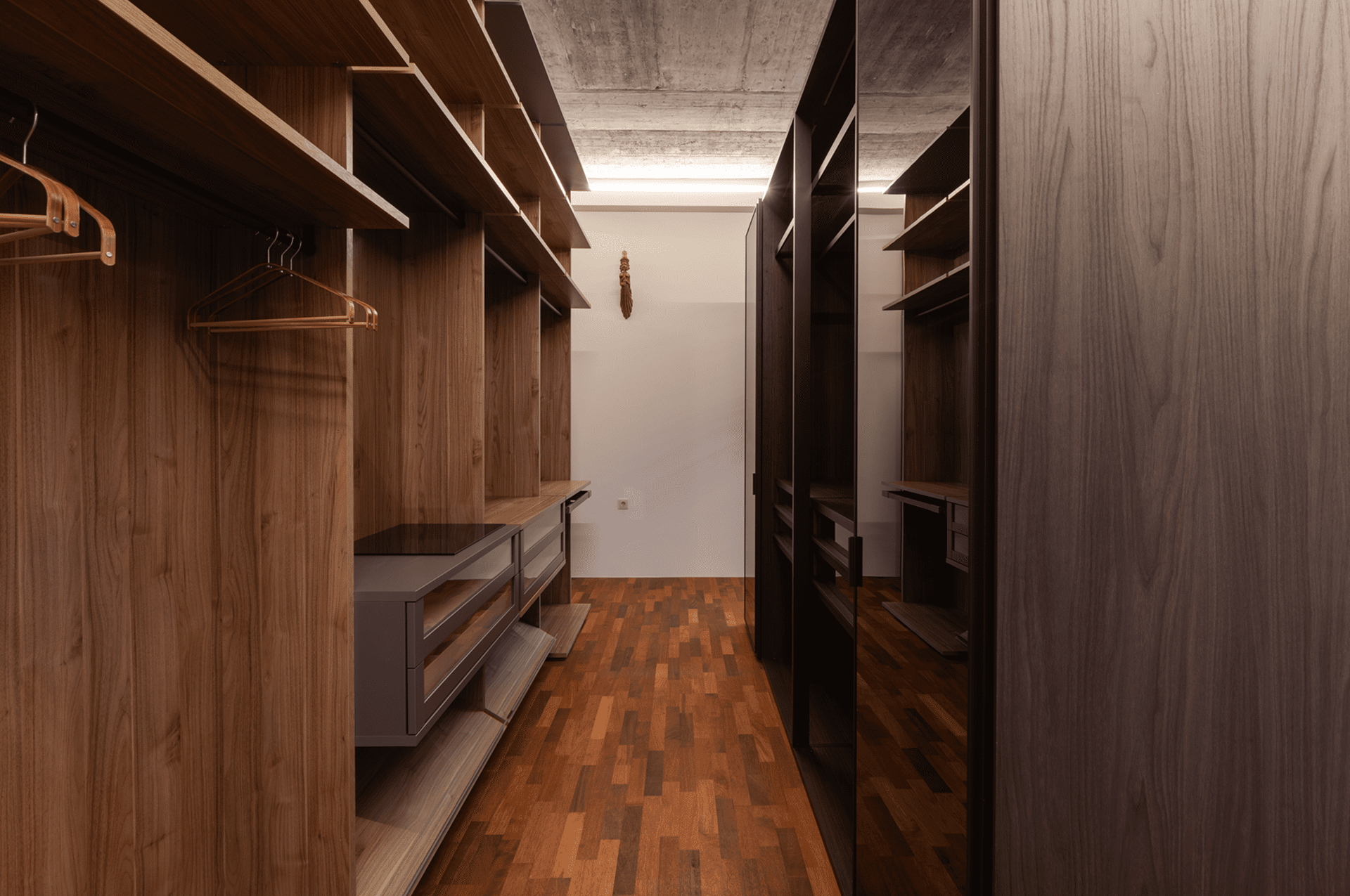 Modern wooden walk-in closet with hangers.